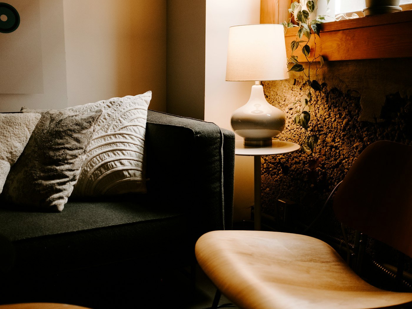 A warm, softly lit lounge corner with cushions, a lamp and trailing plants