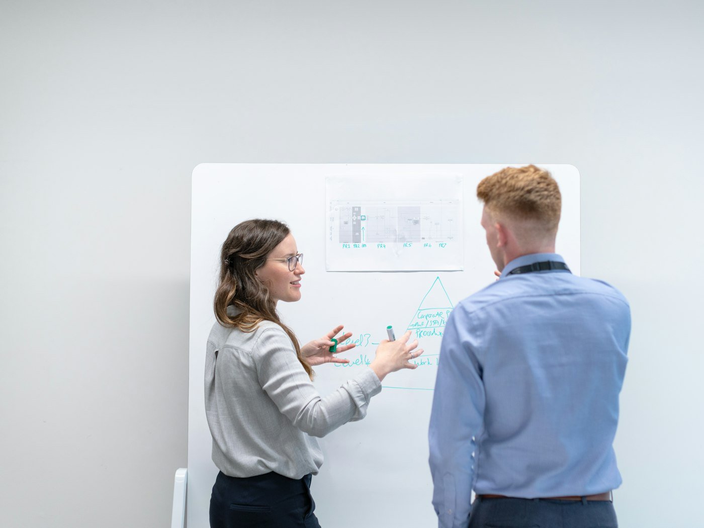 Two colleagues working through ideas together at a whiteboard