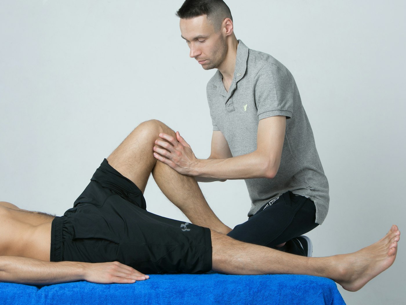A physiotherapist mobilising a patient's knee on a treatment table